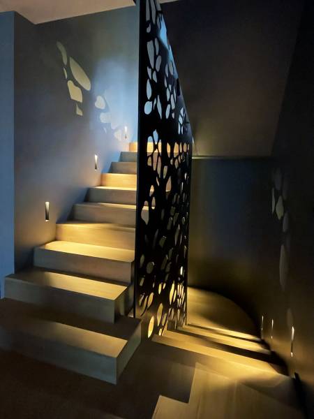 Panneau perforé et jeux de lumière dans une montée d'escalier 